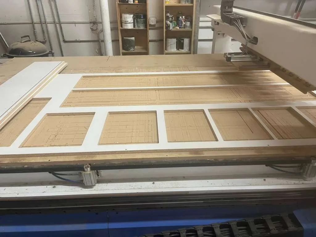 Melamine sheet on the CNC bed with cabinet parts nested and cut