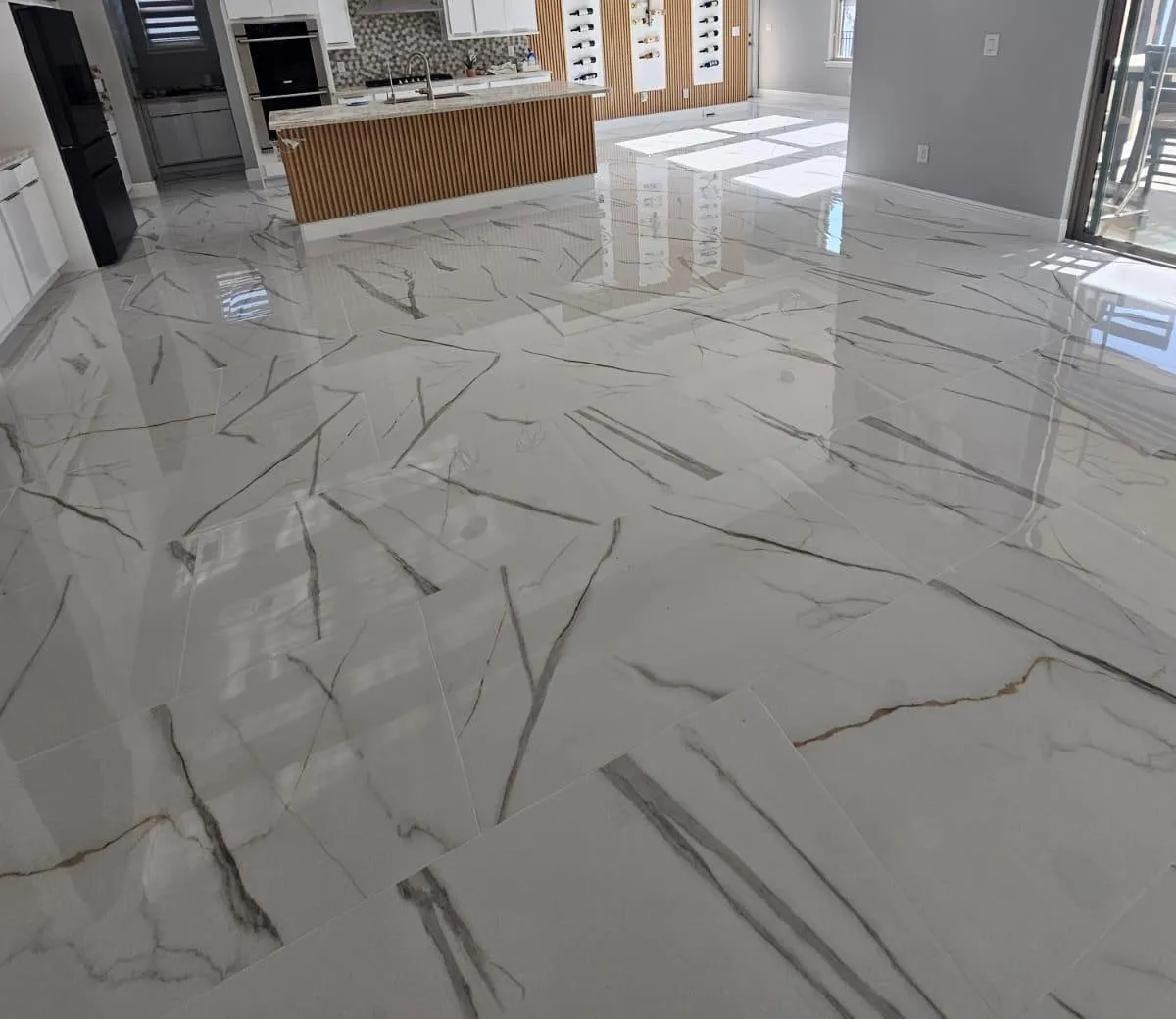 Large-format white marble-look porcelain tile floor, installed by Yoll Remodeling in an open kitchen in Orlando