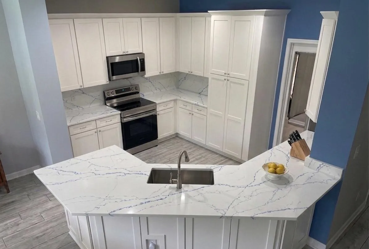 White U-shaped kitchen with shaker cabinets and blue-veined quartz peninsula, remodeled by Yoll Remodeling in Central Florida